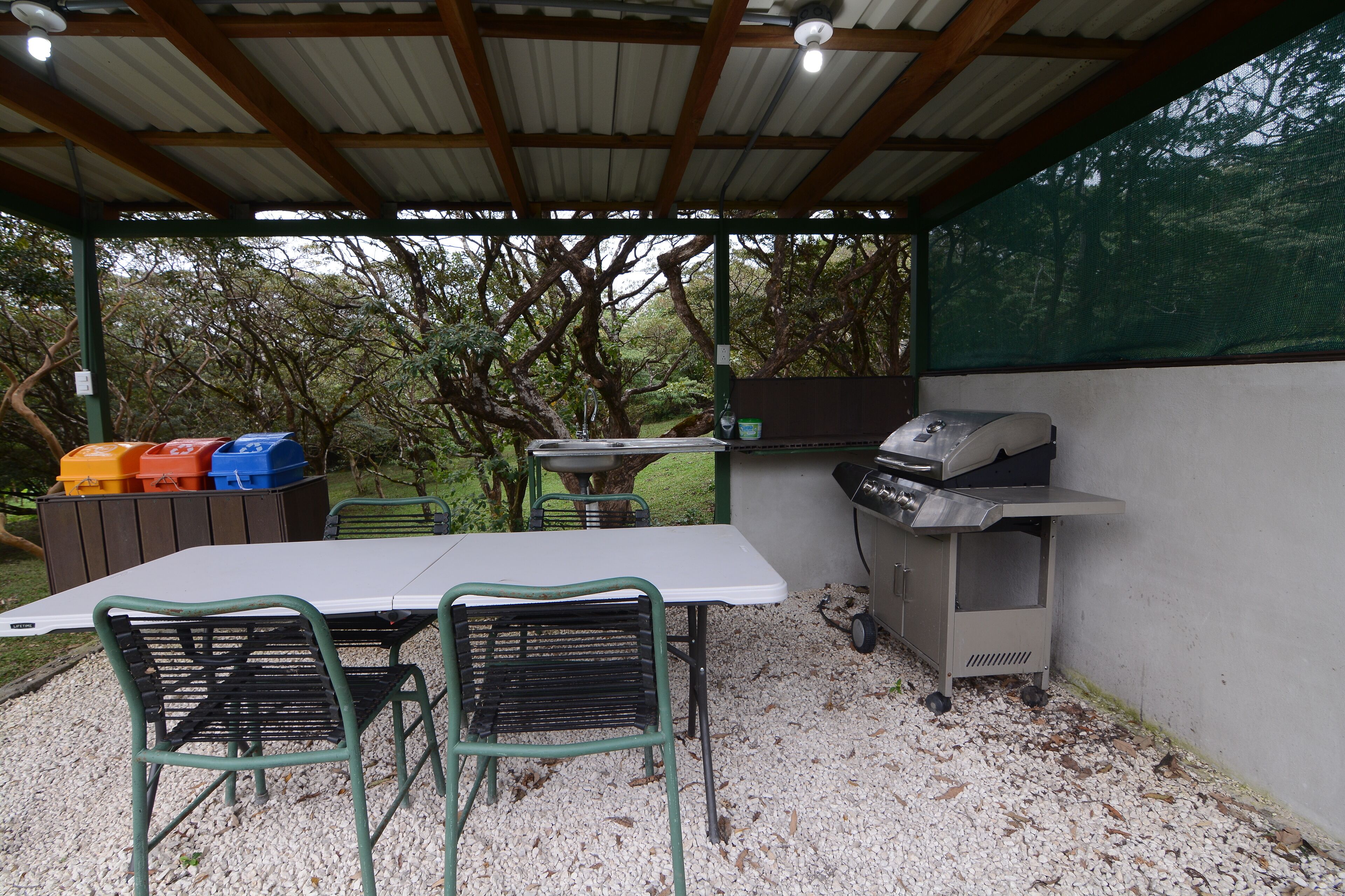 An outdoor patio with a table, chairs, and a grill.
