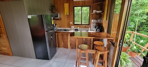 Una cocina compacta con refrigerador, estufa, lavaplatos y taburetes de madera.