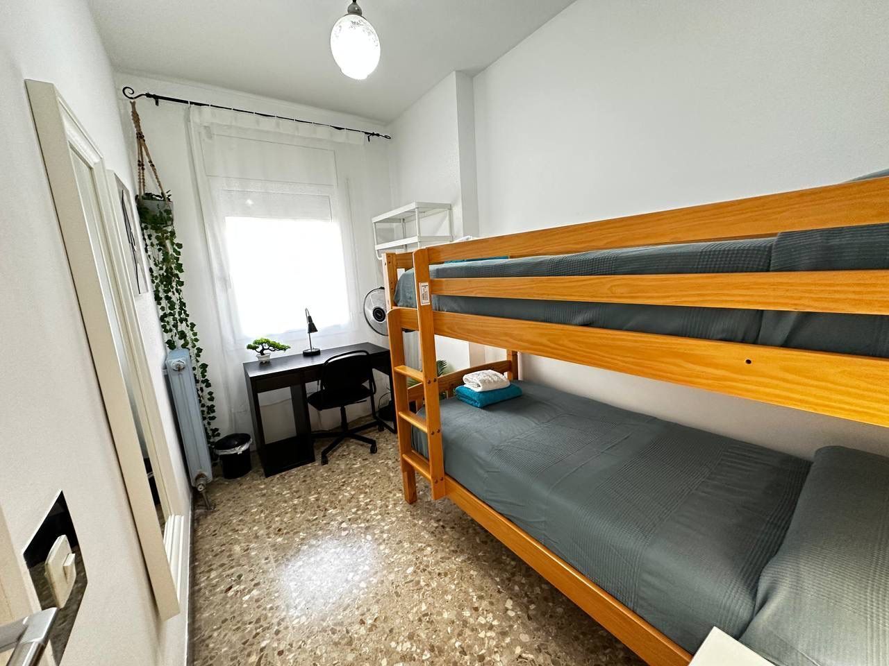 A small, compact room with a bunk bed, a desk, and a chair.