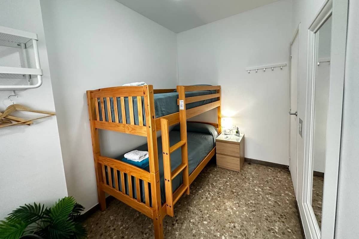 Una stanza piccola e funzionale con letti a castello, un comodino, una lampada a sospensione e una porta.