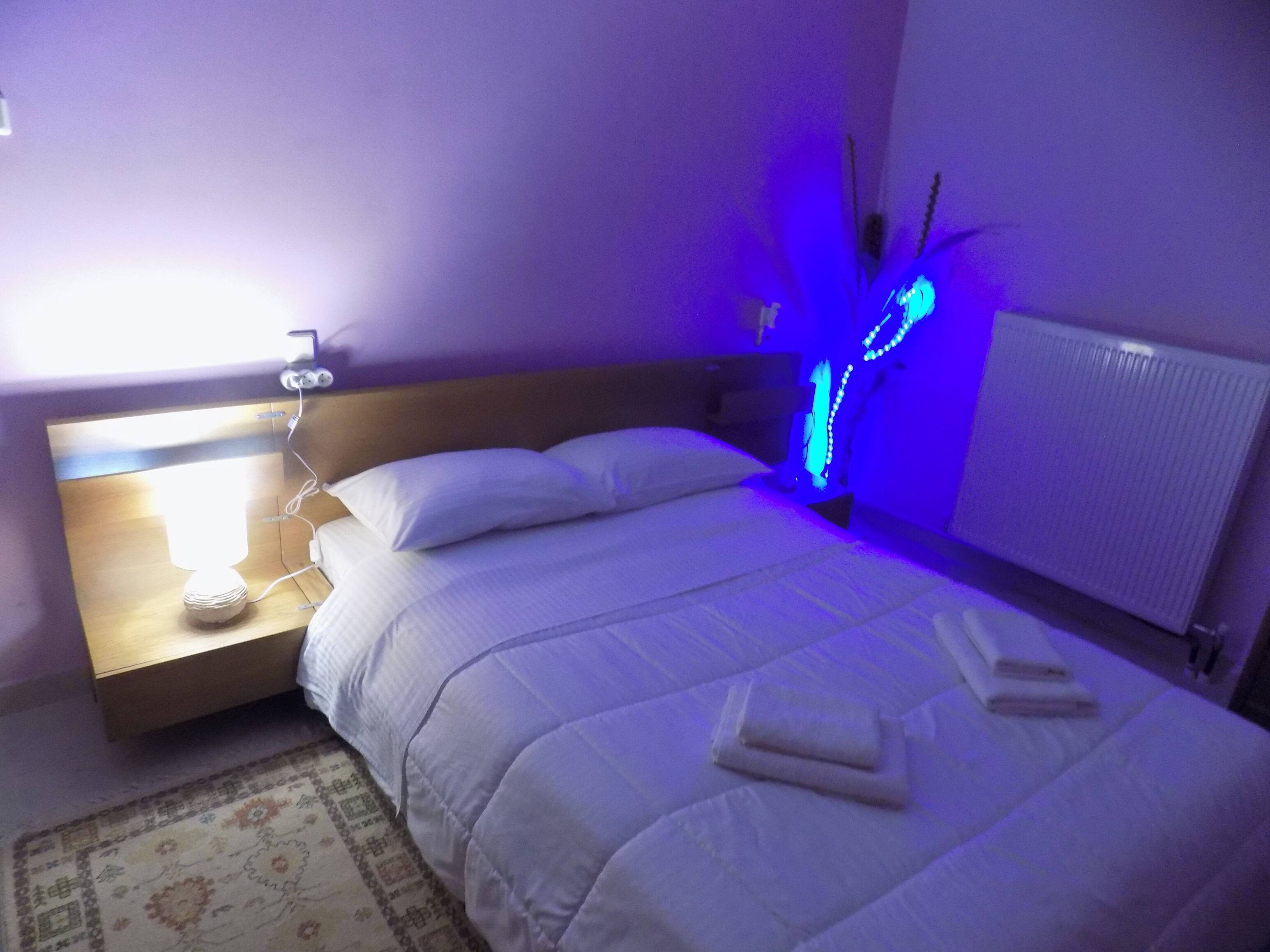 Una camera da letto con un letto, un comodino, una lampada e un lampadario blu.