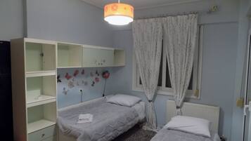 Une chambre avec deux lits, une armoire, un radiateur et une fenêtre avec des rideaux.