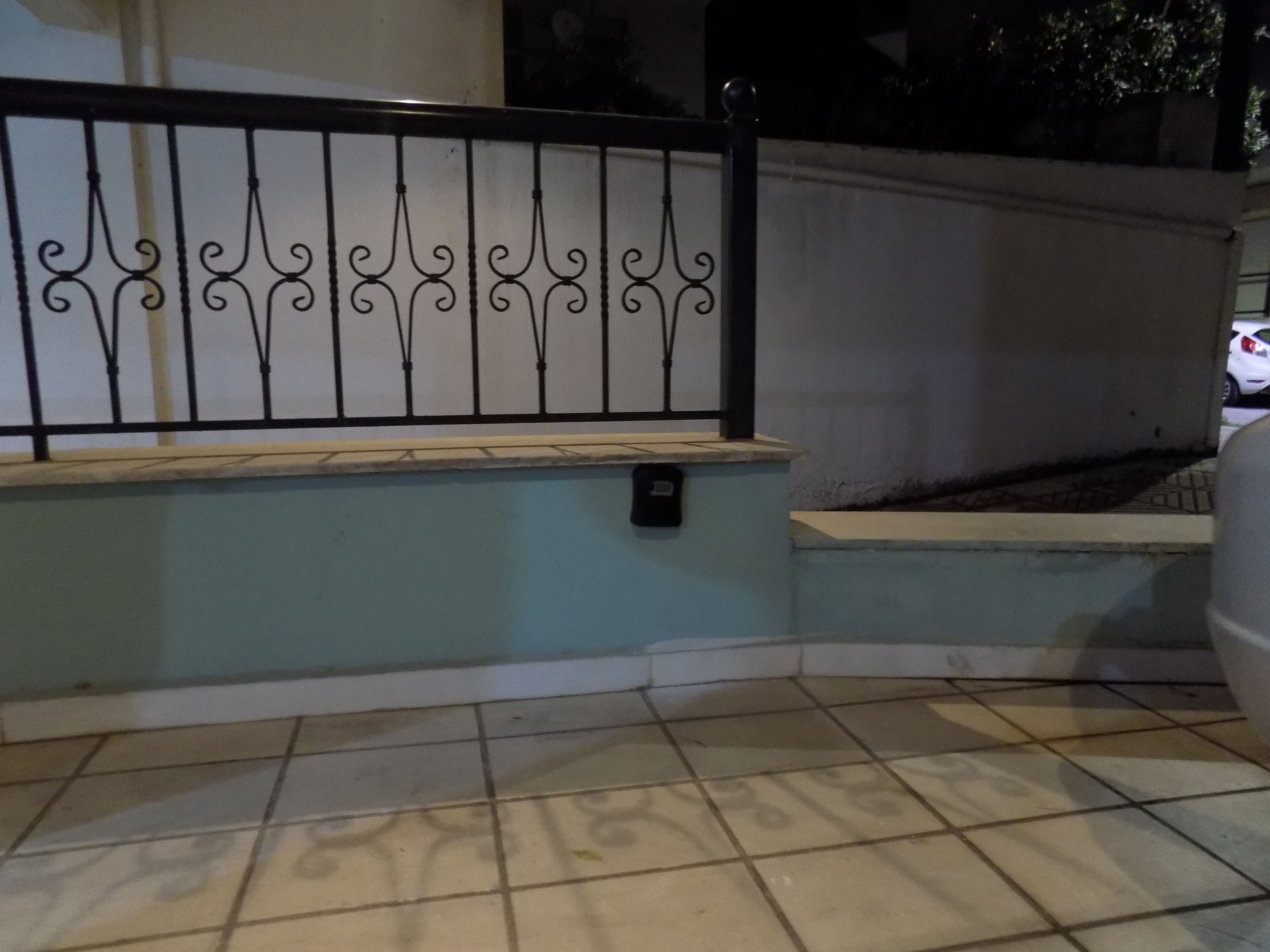 A tiled floor with a metal railing and a wall.