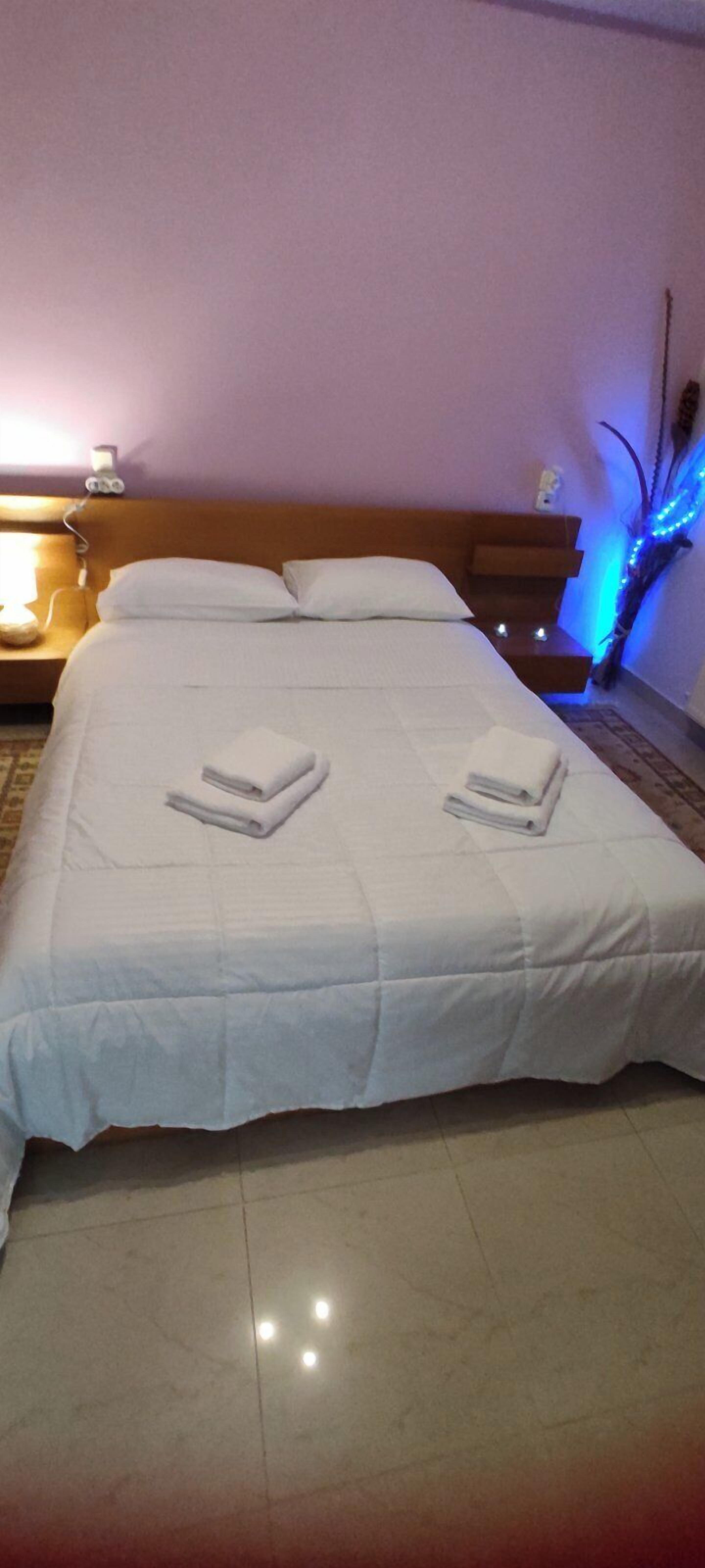 Ein ordentlich gemachtes Bett mit weißen Leinen und zwei gefalteten Handtüchern.