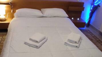 Ein ordentlich gemachtes Bett mit weißen Leinen und zwei gefalteten Handtüchern.