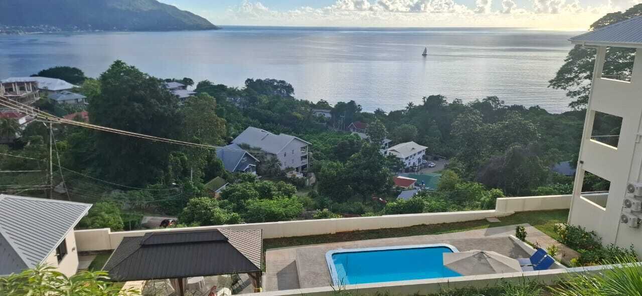 A residential area with a swimming pool, houses, and a view of the sea.