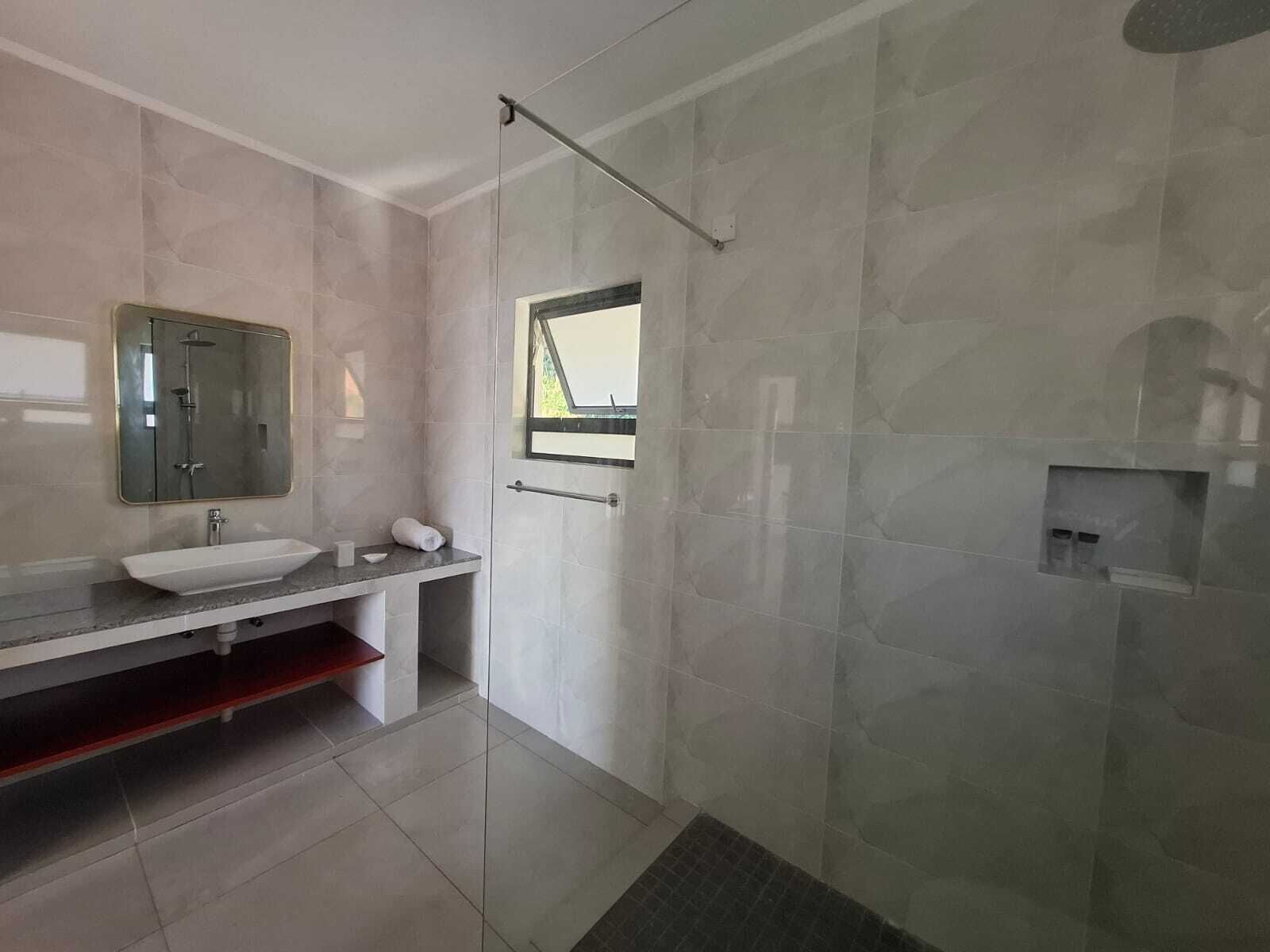 Un bagno moderno con uno specchio grande, un lavandino e una zona doccia.