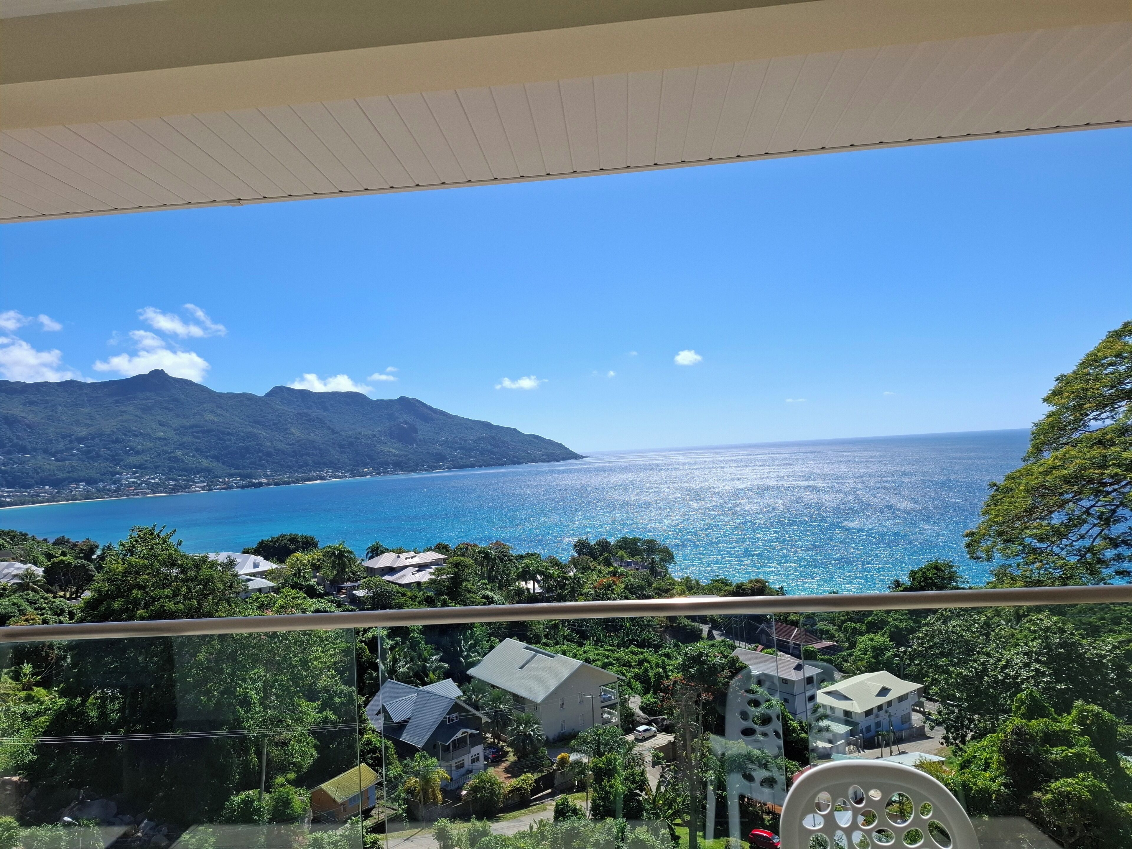 A balcony with a clear view of a coastal landscape, including a mountain range and the sea.
