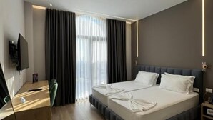 Een moderne hotelkamer met een groot bed, een bureau en een televisie.