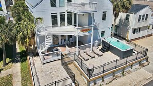 A multi-story house with a balcony, a hot tub, and outdoor seating. - Wow By The Sea (North Myrtle Beach)