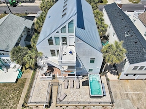 A multi-story building with a rooftop deck, a swimming pool, and a staircase leading to the upper levels.