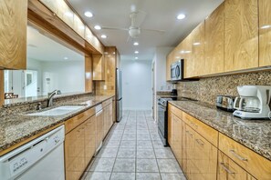 A modern kitchen with granite countertops, wooden cabinets, a microwave, and a dishwasher.