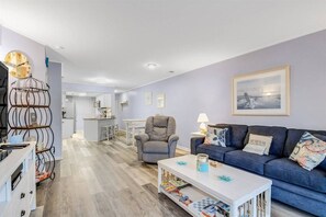 A modern living room with a sofa, a coffee table, and a dining area in the background. - 2 BR condo w/ pool, Ocean Blvd (North Myrtle Beach)