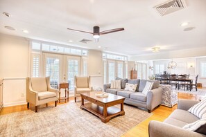 A spacious living room with a large sofa, two armchairs, a coffee table, and a dining area with a table and chairs. - Luxury Home w/ Hottub & Elevator 1Block from Beach (North Myrtle Beach)