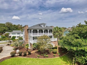 A two-story house with a balcony, surrounded by well-maintained landscaping and trees. - Luxury Home w/ Hottub & Elevator 1Block from Beach (North Myrtle Beach)