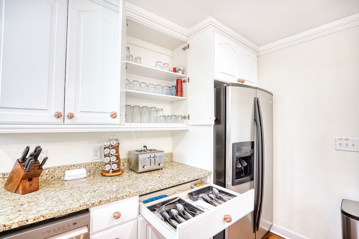 A kitchen with white cabinets, a stainless steel refrigerator, a toaster, and a knife block.