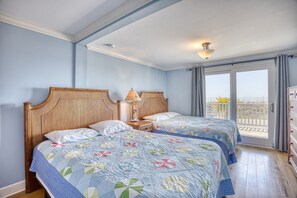 A hotel room with two beds, a balcony with a view, and a wooden headboard.