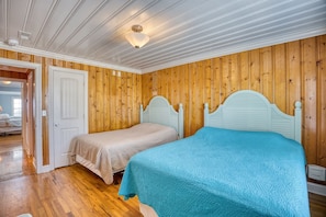 Ein Schlafzimmer mit zwei Betten, Holzwandverkleidung und einer weißen Decke mit einer Leuchte.