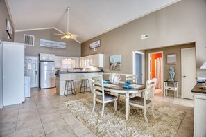 A spacious kitchen with a dining area, white cabinetry, and a ceiling fan.