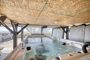 An indoor hot tub area with a wooden ceiling, metal support beams, and a view of the outdoors. - OceanFront/Sleeps 14/Cherry Grove/Golfcart/Hottub (North Myrtle Beach)