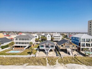 A coastal residential area with multiple two-story houses, a swimming pool, and a beach in the foreground.