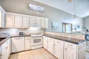 A kitchen with white cabinetry, a stove, and a microwave. - OceanFront/Sleeps 14/Cherry Grove/Golfcart/Hottub (North Myrtle Beach)