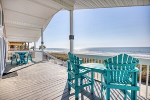 Une terrasse en bois avec une table et des chaises, donnant sur une plage.