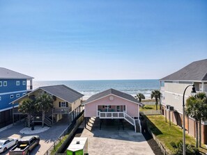 A beachfront property with a central building, a parking area, and a view of the ocean.
