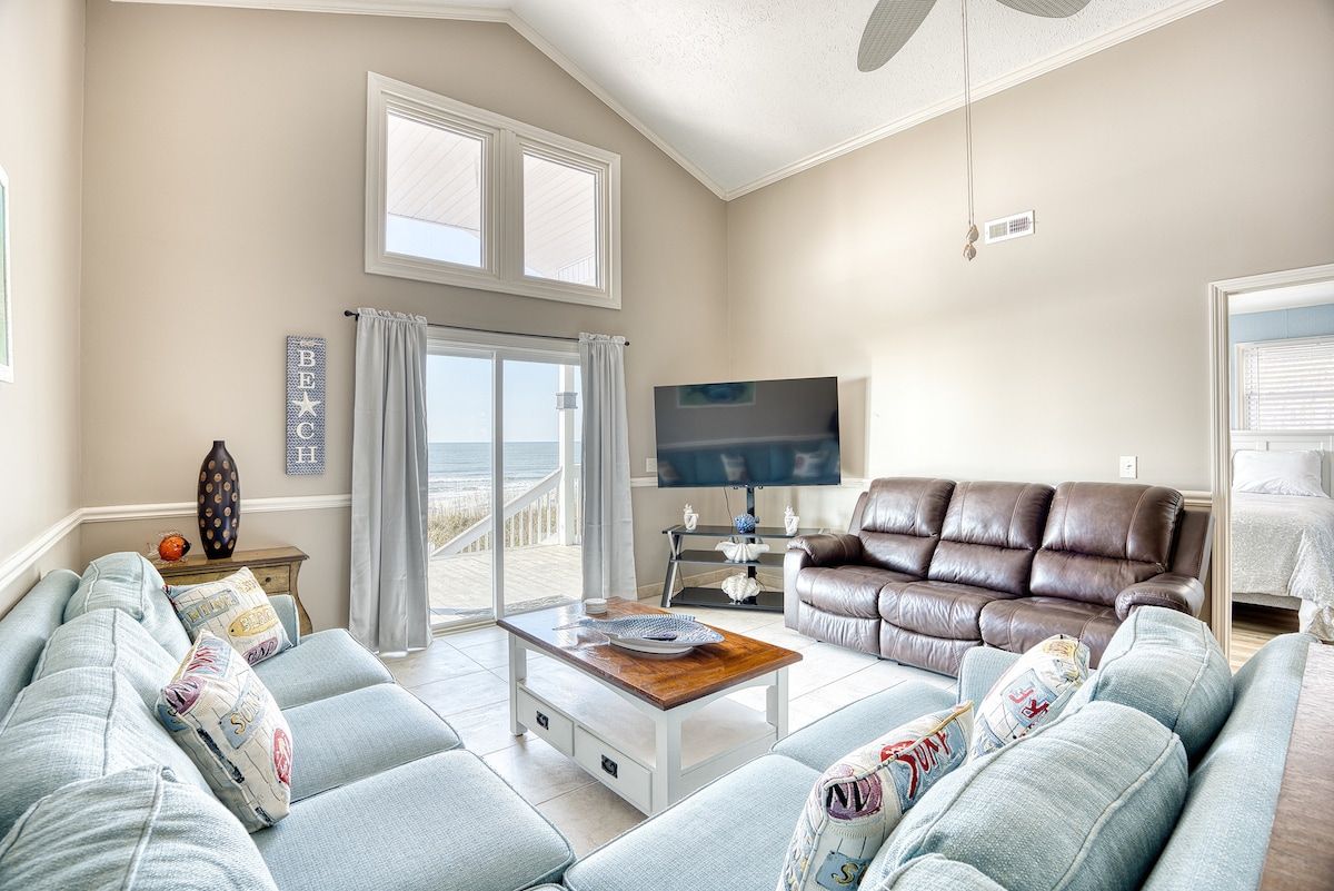 A living room with a sofa, a coffee table, a TV, and a view of the outdoors.