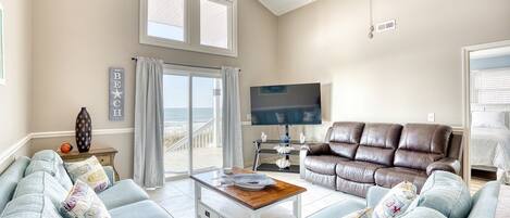 A living room with a sofa, a coffee table, a TV, and a view of the outdoors.
