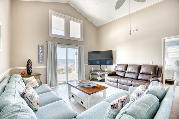 A living room with a sofa, a coffee table, a TV, and a view of the outdoors.