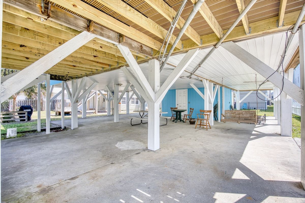 An open-air structure with a concrete floor, wooden beams, and a metal roof.