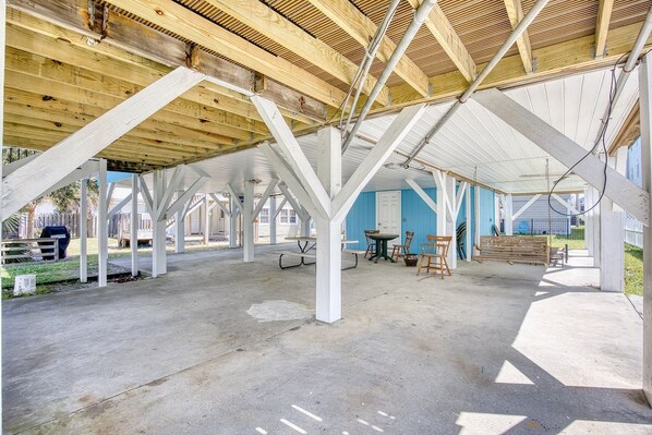 An open-air structure with a concrete floor, wooden beams, and a metal roof.