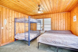 A room with wooden walls, a bunk bed, a single bed, a ceiling fan, and a window with blinds. - 4 BR House in Cherry Grove, 1 Block from beach (North Myrtle Beach)