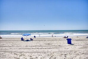 A beach with clear skies, footprints, and a few people.