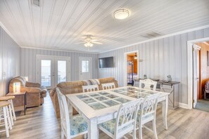 A spacious living area with a dining table, sofas, and a television.