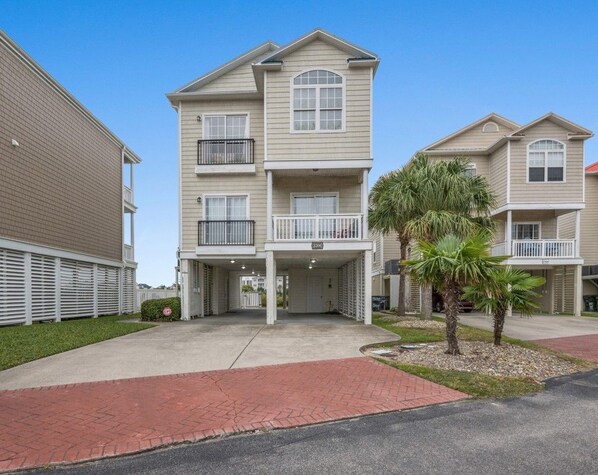 A two-story residential building with a flat roof, a covered front porch, and a small palm tree in the front yard. - 5BR Waterfront Home w/ Pool, hotub, & elevator (North Myrtle Beach)