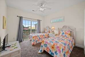 A bedroom with two beds, a ceiling fan, a window with curtains, and a television on a stand. - 5BR Waterfront Home w/ Pool, hotub, & elevator (North Myrtle Beach)