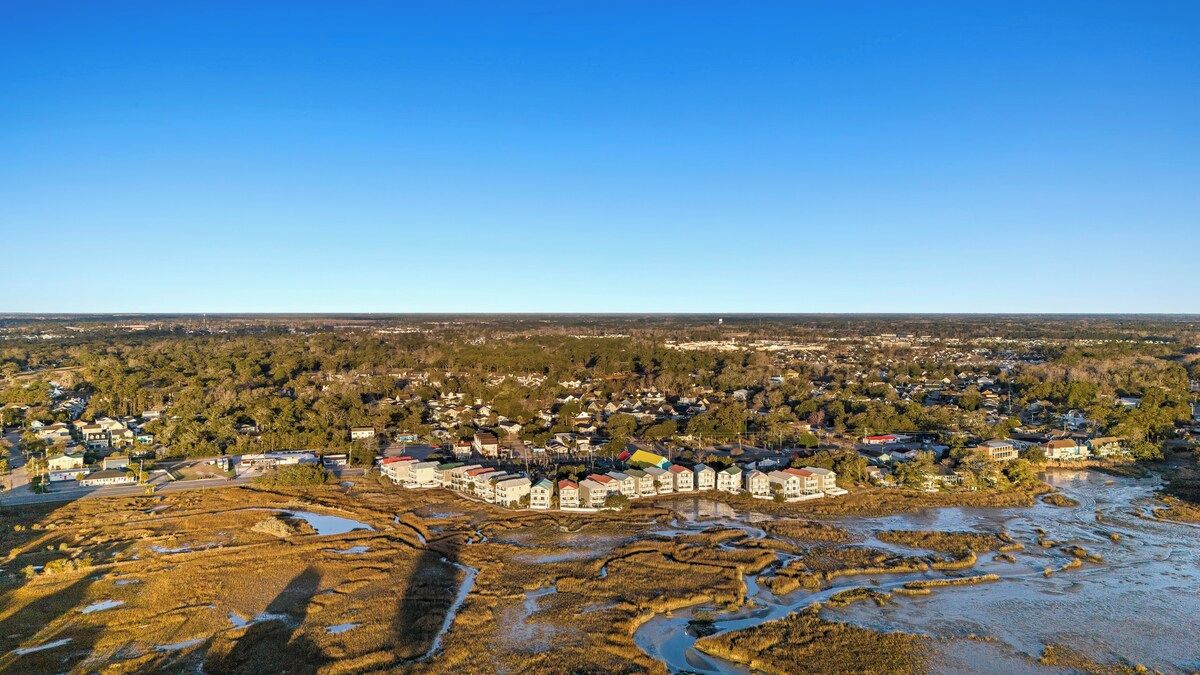 A coastal town with a riverfront, buildings, and a clear sky.
