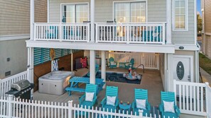 Une maison à deux étages dotée d’un patio couvert comprenant un espace salon extérieur, un jacuzzi et un barbecue.