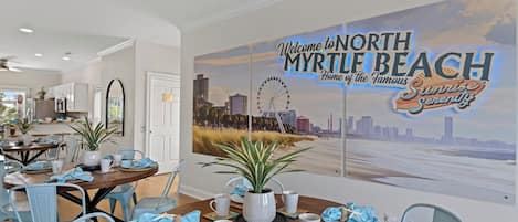 A dining area with a cityscape mural, a round table set for four, and light blue chairs.