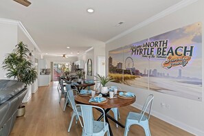 Een eetgedeelte met een ronde tafel, stoelen en een muurschildering van North Myrtle Beach.