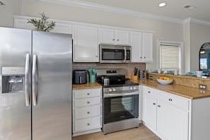 A modern kitchen with stainless steel appliances, white cabinetry, and a granite countertop. - Large Luxury Water Front W/ Pool, HotTub, Elevator (North Myrtle Beach)