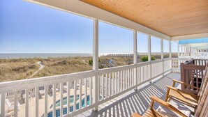 Une terrasse en bois offrant une vue sur la plage et l’océan.