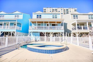 Un hotel frente a la playa con piscina, balcones y una cerca blanca.