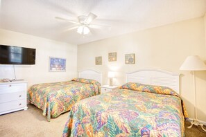 A bedroom with two beds, a ceiling fan, a TV, a dresser, and wall art. - 6 BR OceanFront w/ Heated Pool/Hottub Cherry Grove (North Myrtle Beach)