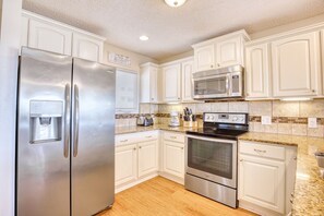 A kitchen with white cabinets, a stainless steel refrigerator, a microwave, and an oven.