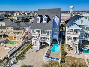 A multi-story residential building with a pool, balconies, and a clear view of the surrounding neighborhood.