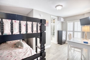 Un dormitorio con cama, escritorio y cómoda.