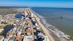 An aerial view of a coastal town with a long beach, a pier extending into the water, and a mix of residential and commercial buildings. - 52 Week High (North Myrtle Beach)
